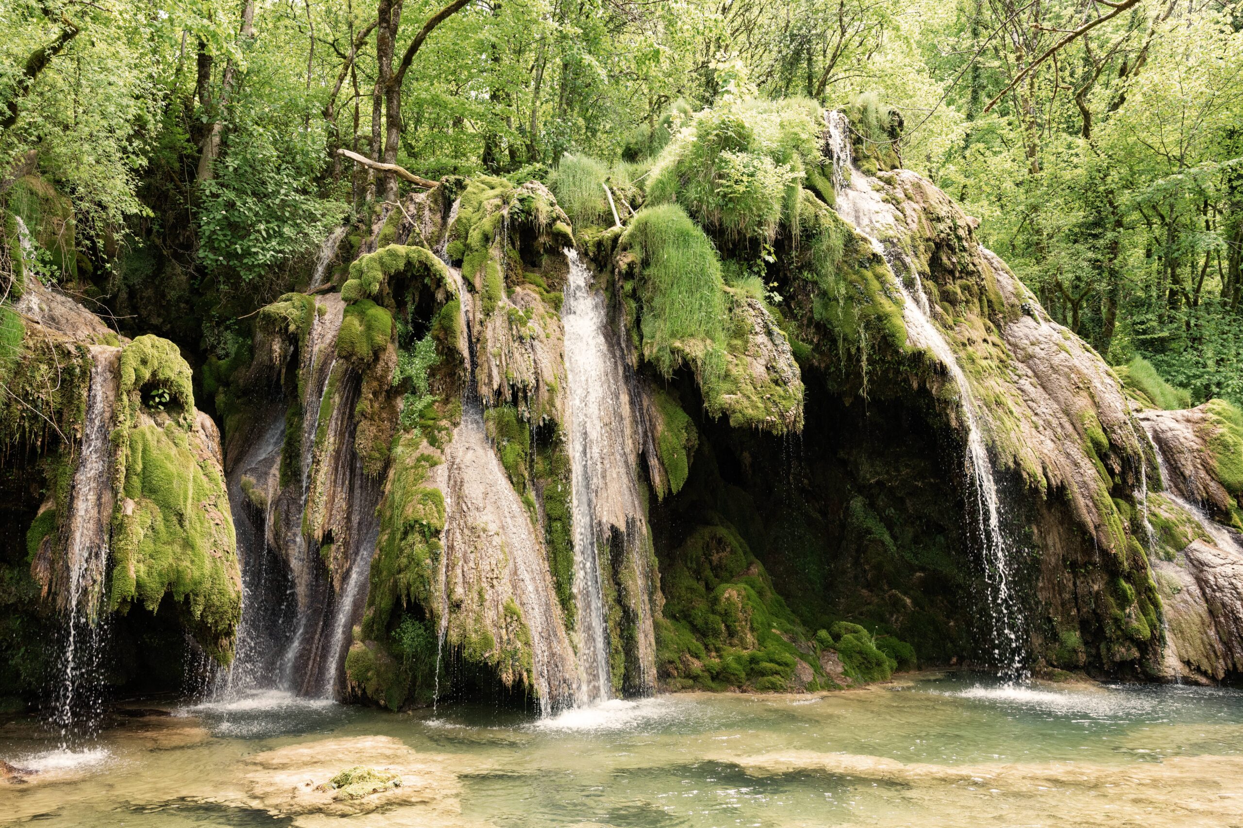 Cascades des Tufs dans le Jura sous une lumière dorée, illustrant l'ancrage local de TALAKY Studio, agence web dans le Jura